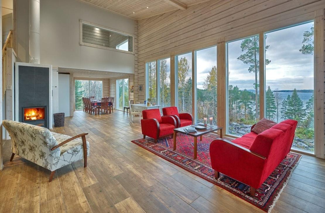 Vaalea ja korkea oleskelutila, jossa isot ikkunat ja punainen sohvaryhmä