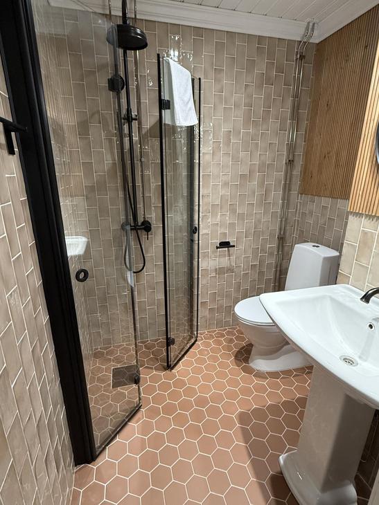 Kylpyhuone, jossa punertavat kuusikulmaiset lattialaatat.