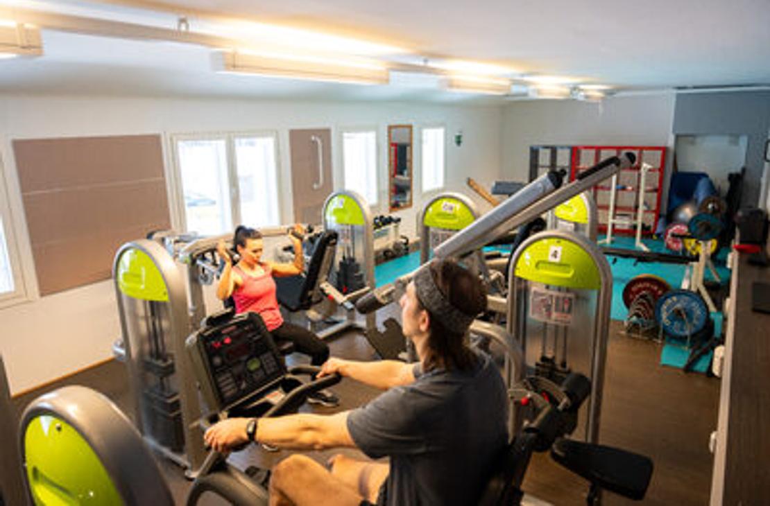 Kaksi henkilöä treenaamassa Kolikeskuksen kuntosalilla kuntosalilaitteissa