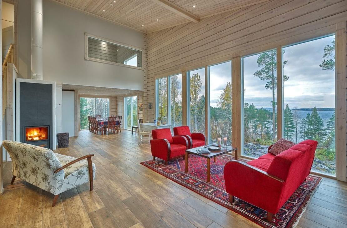 Vaalea ja korkea oleskelutila, jossa isot ikkunat ja punainen sohvaryhmä