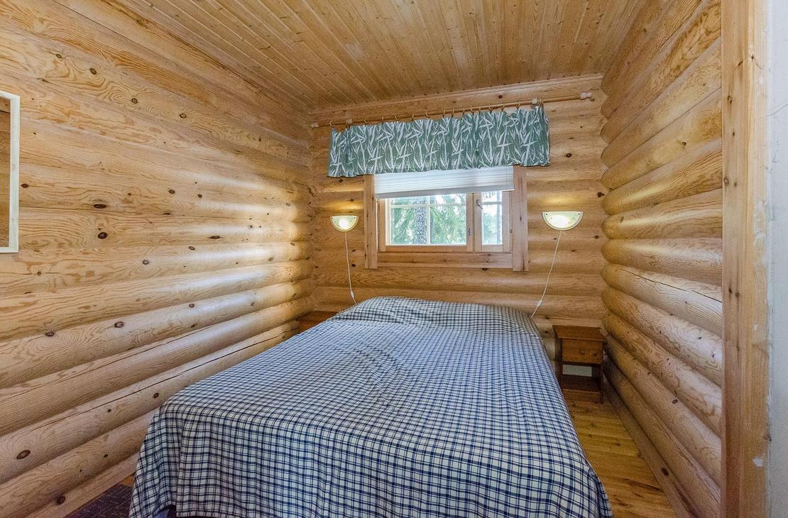 Hirsiseinäinen makuuhuone, jossa kahden hengen leveä sänky