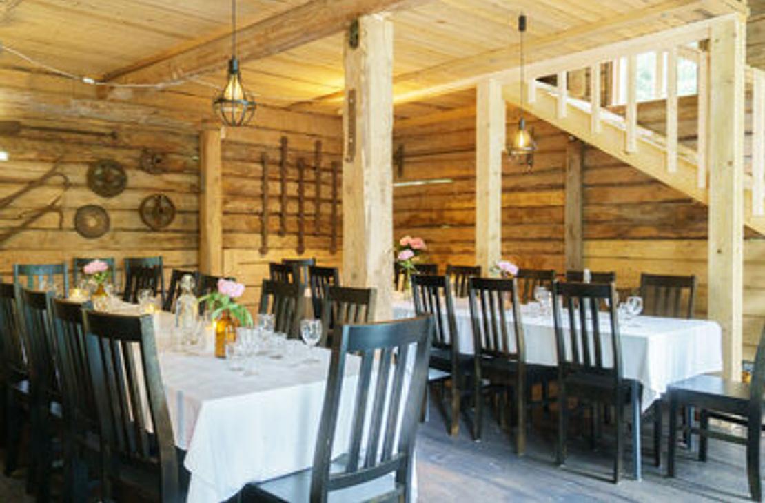 Venejoen Myllyn hirsiset sisätilat, jossa katettuja pöytiä