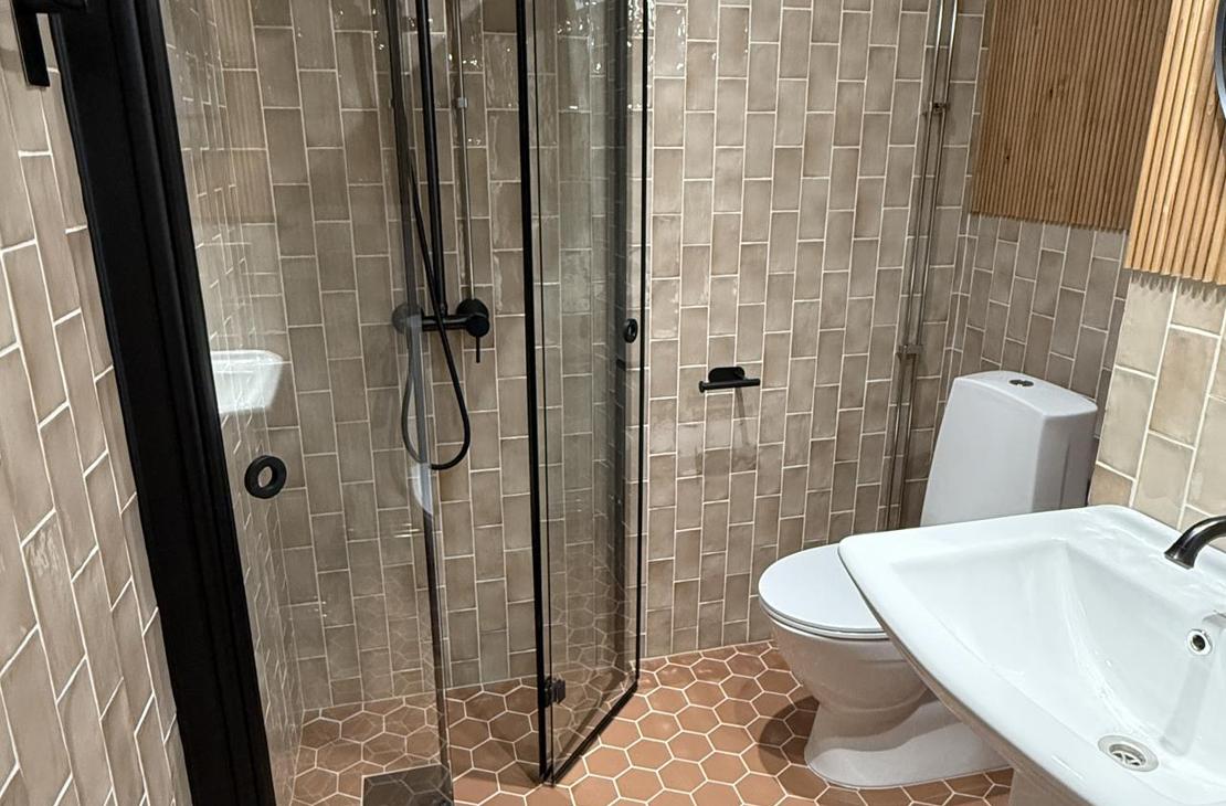 Kylpyhuone, jossa punertavat kuusikulmaiset lattialaatat.