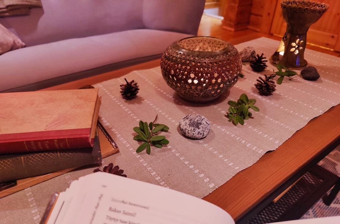 Pöydällä pitsikeraaminen kynttilä, kirjoja ja luonnon koristeita