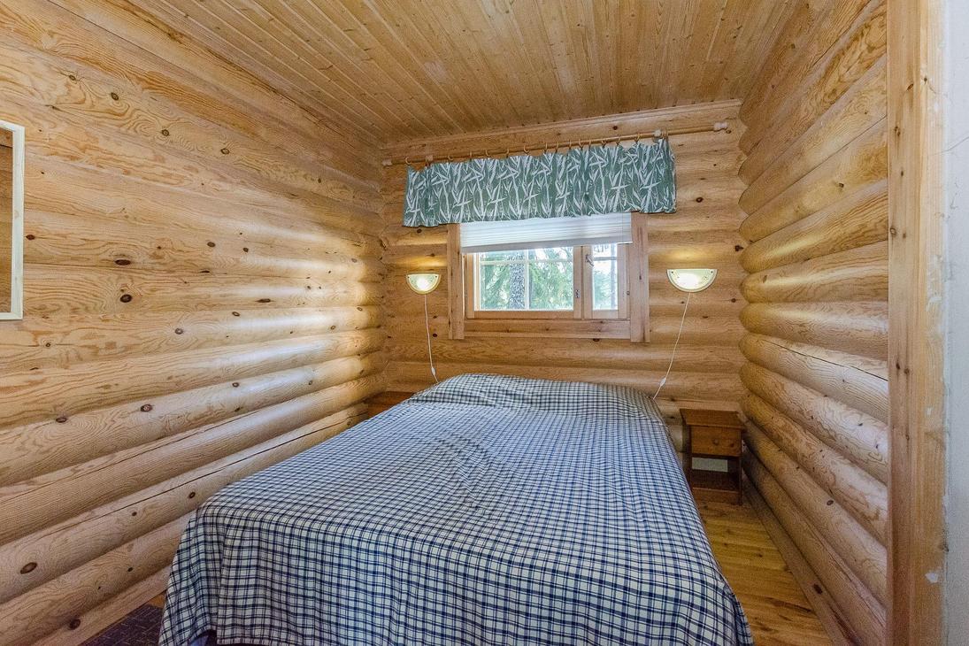 Hirsiseinäinen makuuhuone, jossa kahden hengen leveä sänky