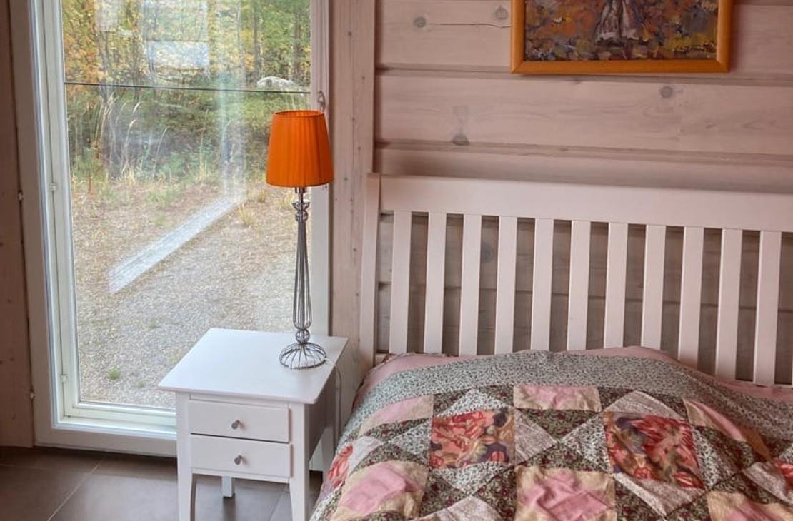 Vaaleanpuna-vihre&auml;-valkoinen tilkkupeitto s&auml;ngyll&auml;, vierell&auml; maisemaikkuna