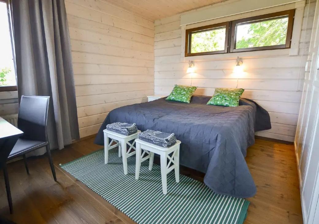 Makuuhuone parivuoteella, vaaleat puuseinät ja vihreät koristetyynyt