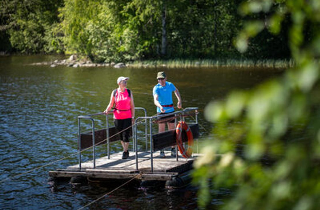 Kaksi retkeilij&auml;&auml; vetolautalla ylitt&auml;m&auml;ss&auml; vesist&ouml;&auml;