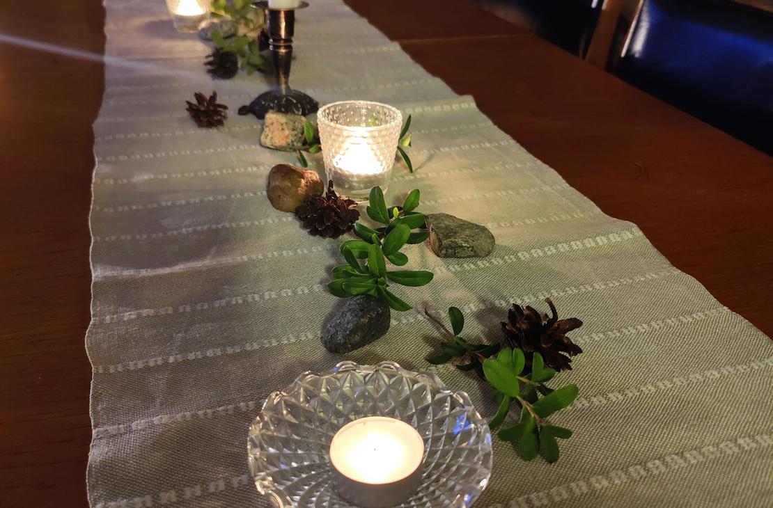 Kotikirjaston tumma puup&ouml;yt&auml;, jonka p&auml;&auml;ll&auml; pellavaliina, kynttil&ouml;it&auml;, m&auml;nnynk&auml;pyj&auml; ja puolukanvarpuja