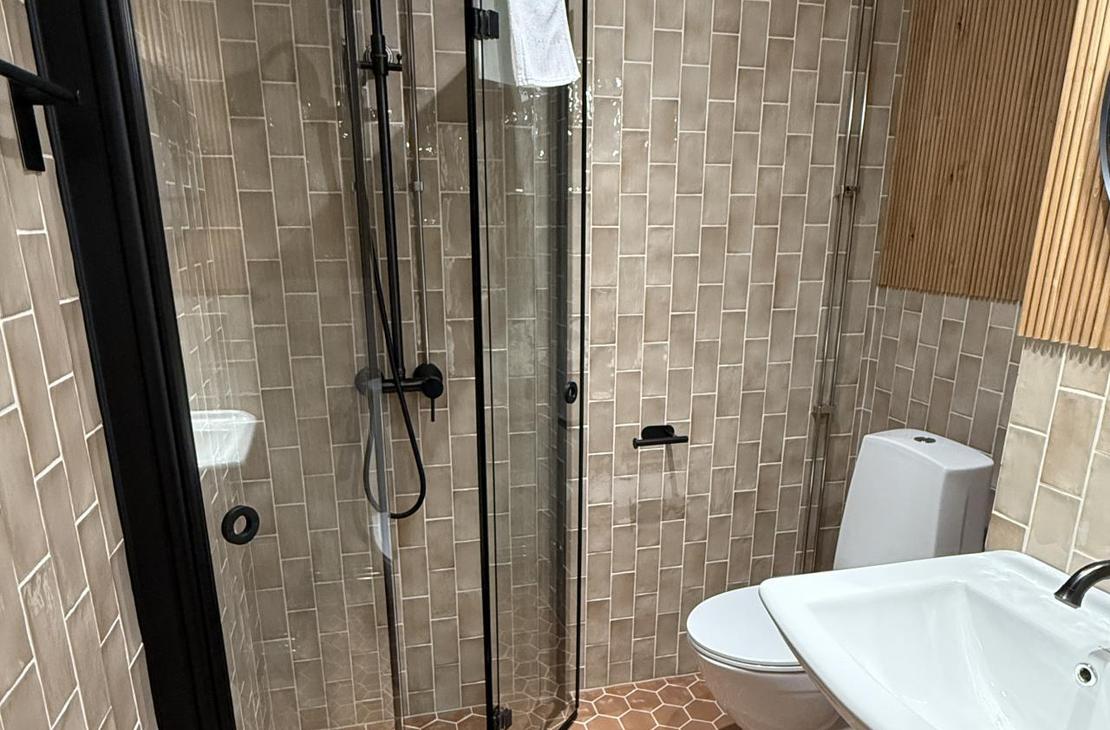 Kylpyhuone, jossa punertavat kuusikulmaiset lattialaatat.