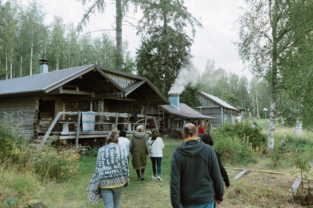 Ihmisi&auml; k&auml;velem&auml;ss&auml; kohti harmaata melko suurta savusaunaa