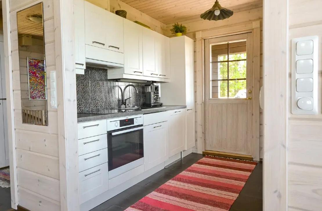 Mökissä on valkoiset keittiökaapit ja keittiöstä on käynti terassille