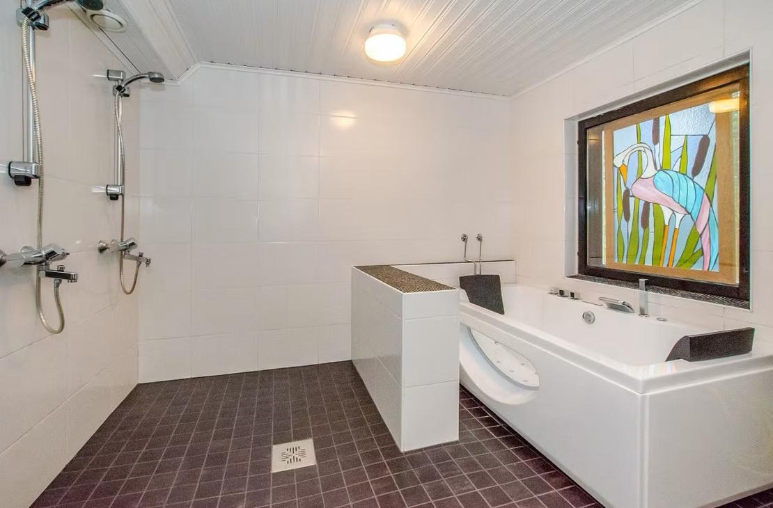 Suihku- ja kylpyhuone, jossa linjakas poreamme.