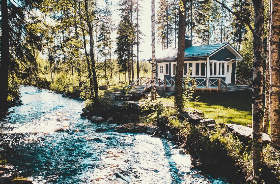 Kuohu mökki pienen vaahtoavan kosken rannalla