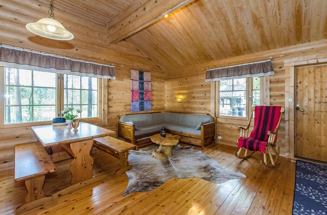 Hirsisen mökin oleskelunurkkaus, jossa pirtinpöytä ja kulmasohva