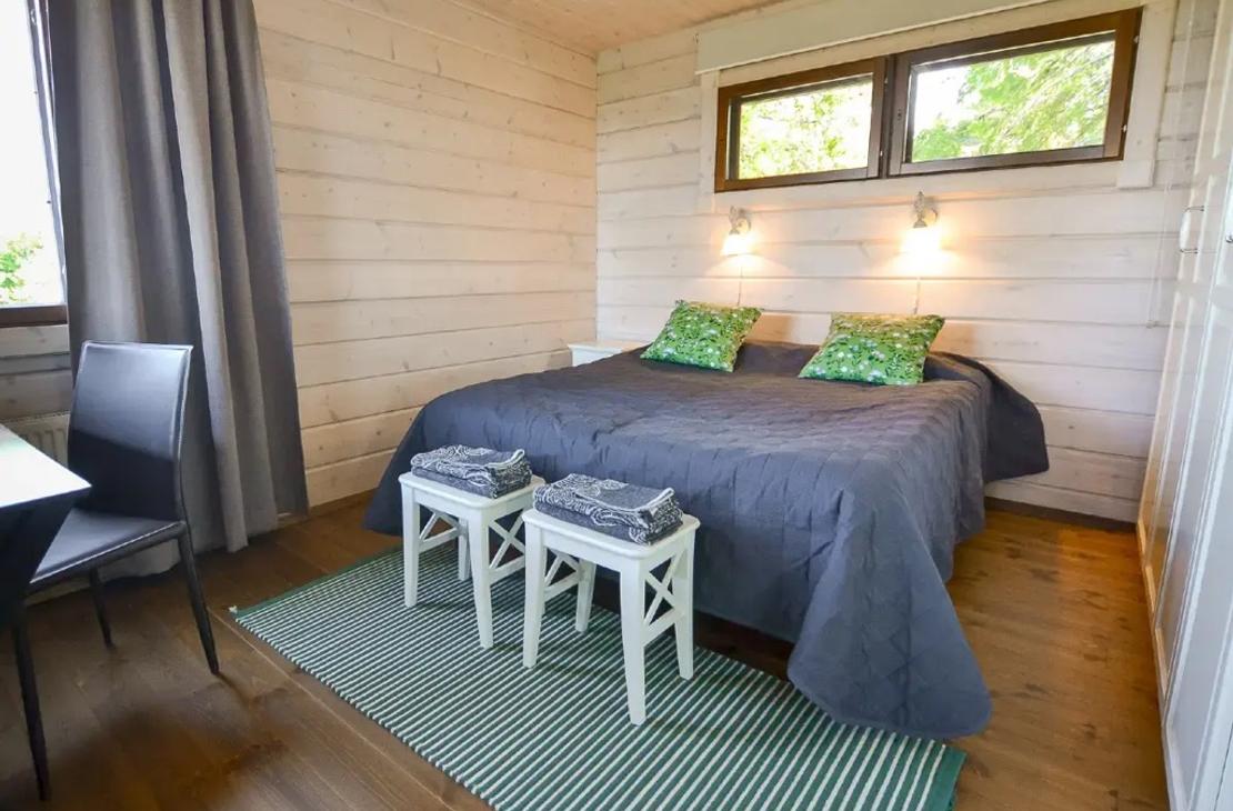 Makuuhuone parivuoteella, vaaleat puusein&auml;t ja vihre&auml;t koristetyynyt