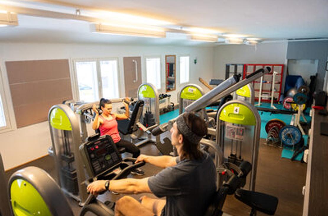 Kaksi henkilöä treenaamassa Kolikeskuksen kuntosalilla kuntosalilaitteissa
