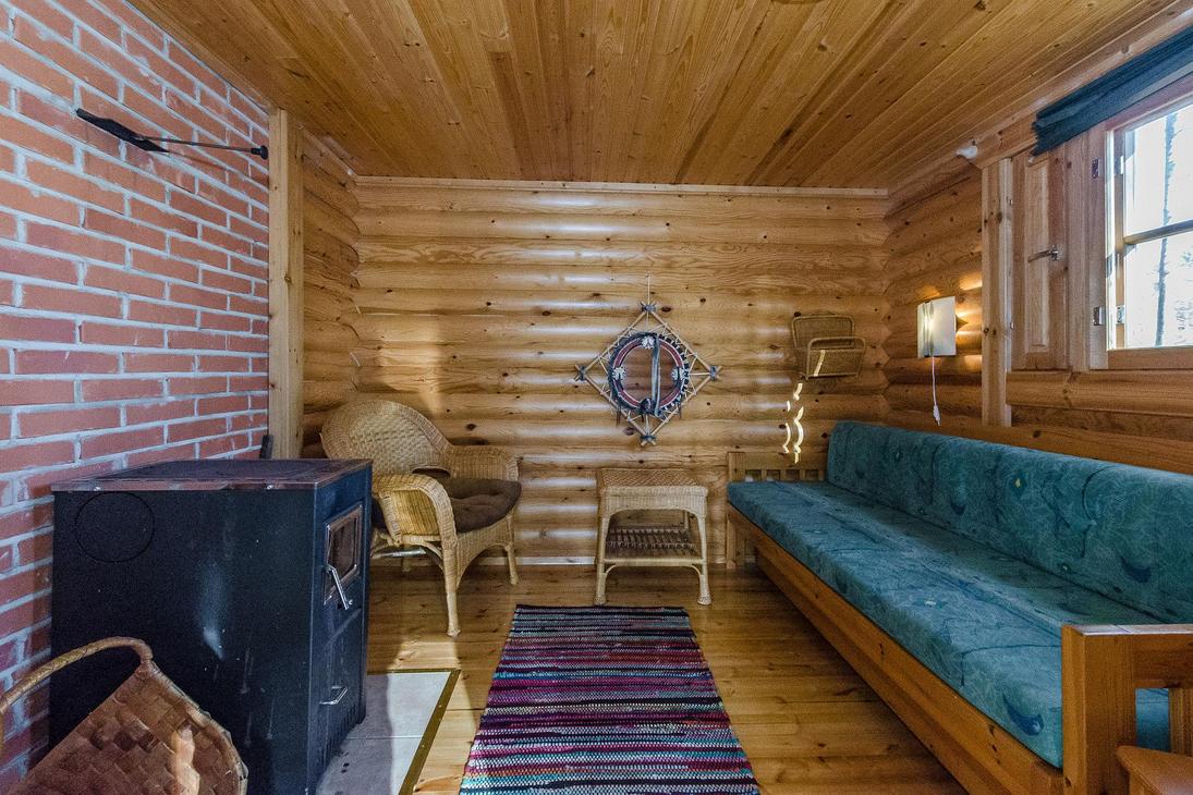 Tilava saunan eteinen, jossa levitettävä sohva ja takka