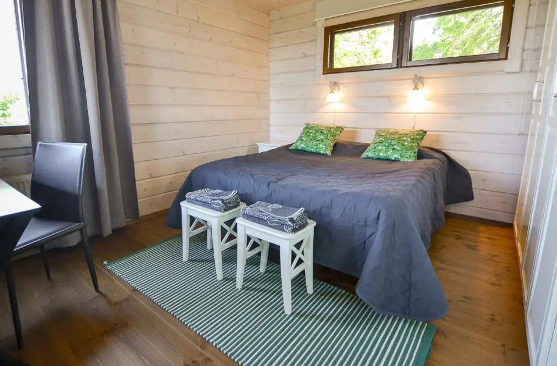 Makuuhuone parivuoteella, vaaleat puusein&auml;t ja vihre&auml;t koristetyynyt