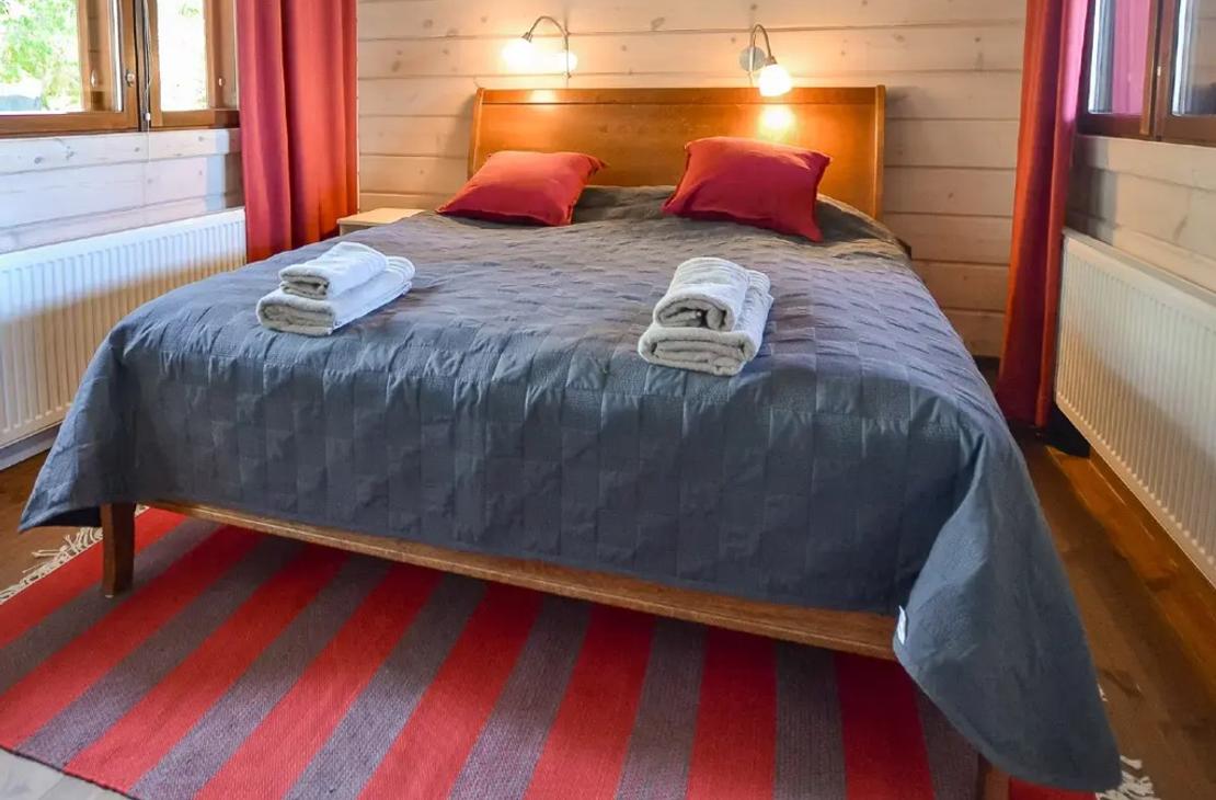 Makuuhuone parivuoteella, punainen tehosteväri verhoissa ja tyynyissä