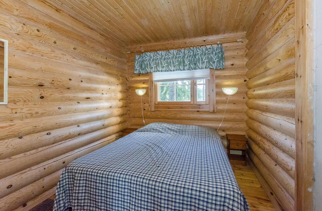 Hirsiseinäinen makuuhuone, jossa kahden hengen leveä sänky