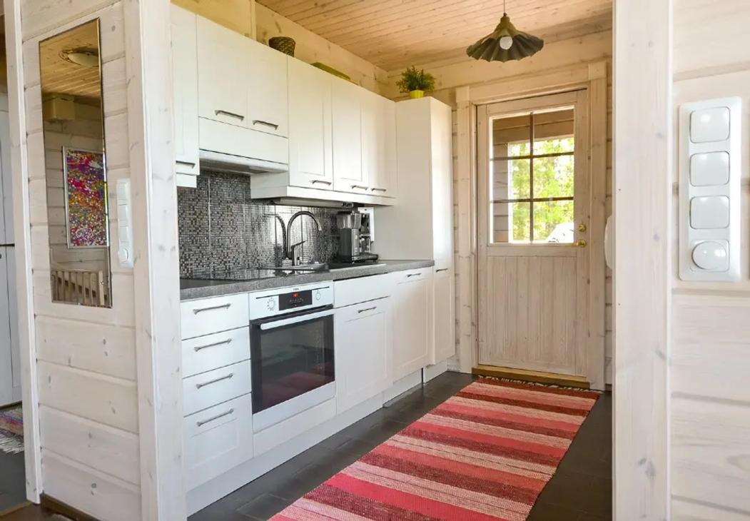Mökissä on valkoiset keittiökaapit ja keittiöstä on käynti terassille