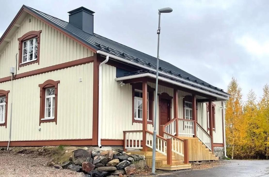 Vaalea kaksikerroksinen puutalo, jossa on viisi huonetta ja ruosteenväriset koristelaudat.