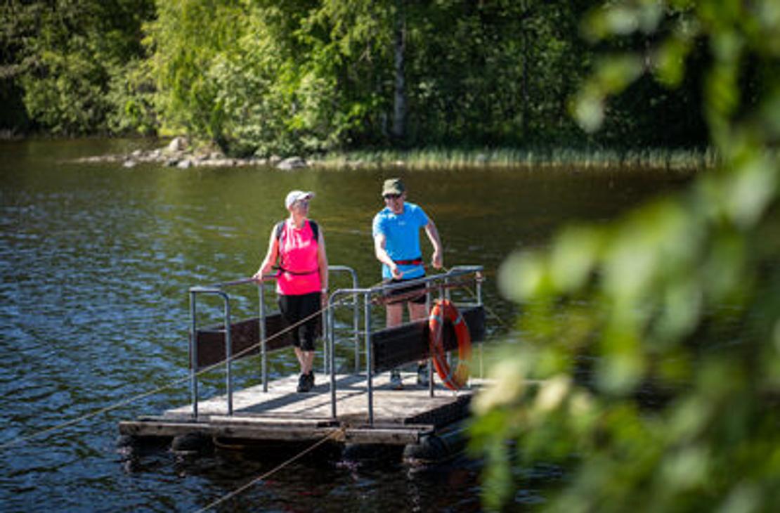 Kaksi retkeilij&auml;&auml; vetolautalla ylitt&auml;m&auml;ss&auml; vesist&ouml;&auml;