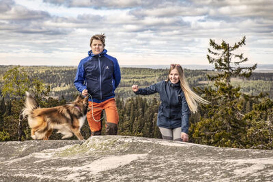 Kaksi retkelij&auml;&auml; ja koira nousemassa kalliolle Kolin huipulla