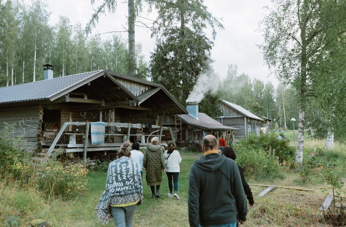 Ihmisiä kävelemässä kohti harmaata melko suurta savusaunaa