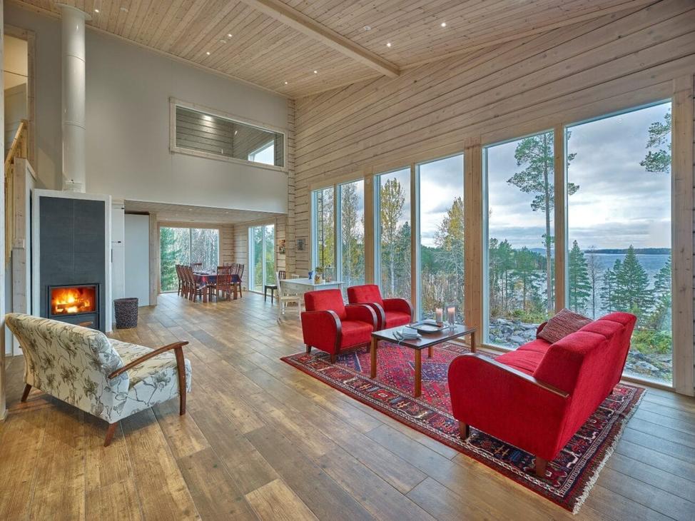 Vaalea ja korkea oleskelutila, jossa isot ikkunat ja punainen sohvaryhmä