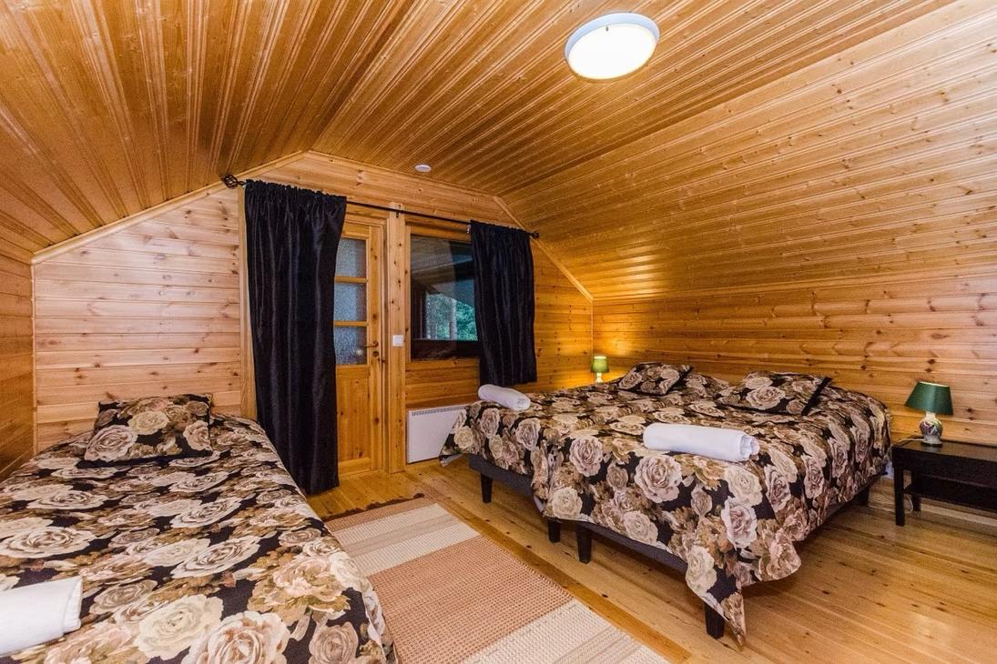 Yläkerran makuuhuone, jossa kalteva katto ja värikkäät tummapohjaiset sänkypeitot