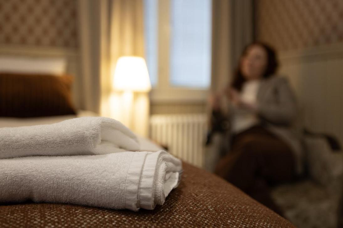 Vaalean ja punaruskean s&auml;vyinen huone, jossa yksi s&auml;nku ja nojatuoli