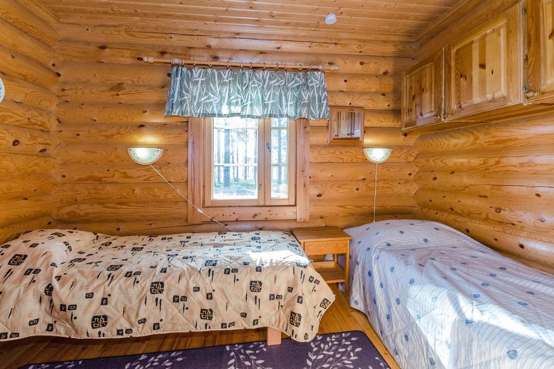 Hirsiseinäinen makuuhuone, jossa kaksi erillistä sänkyä