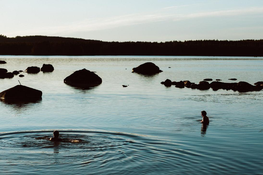 Ihmisi&auml; uimassa tyynell&auml; j&auml;rvell&auml; illan h&auml;myss&auml;