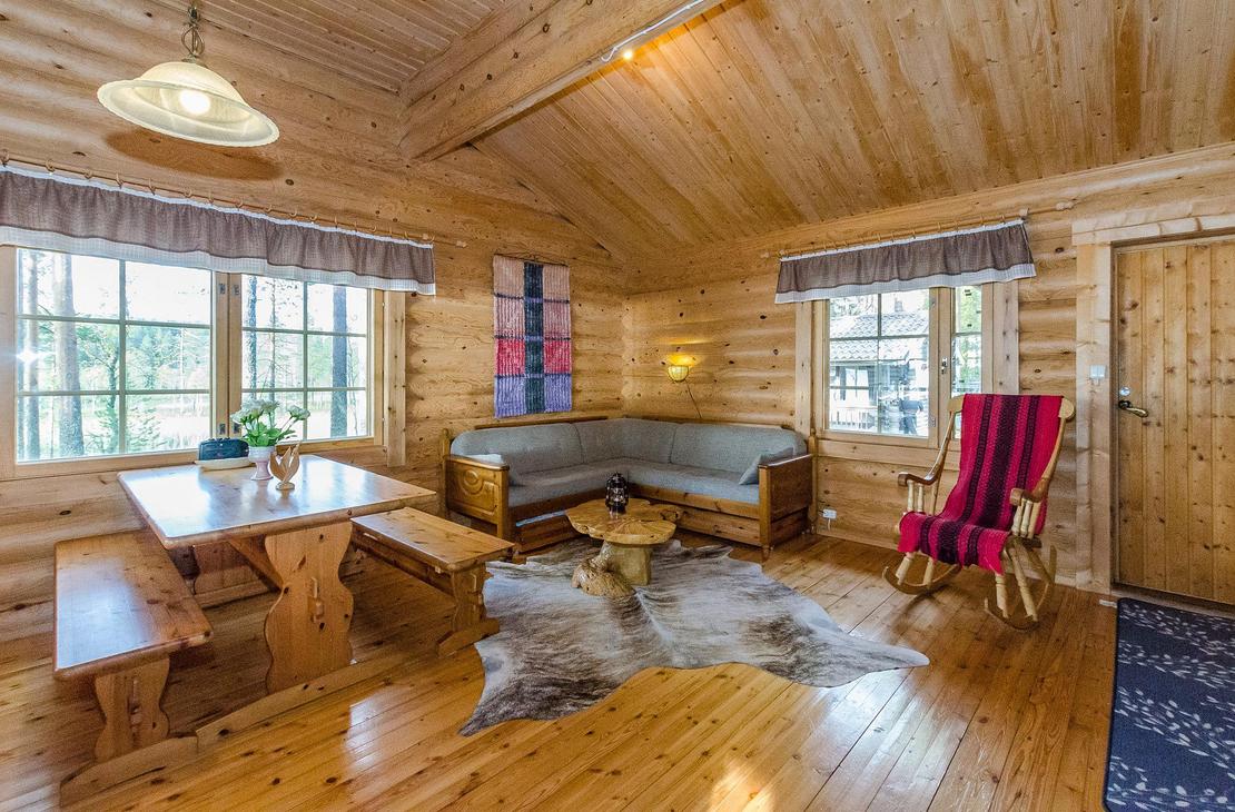 Hirsisen mökin oleskelunurkkaus, jossa pirtinpöytä ja kulmasohva