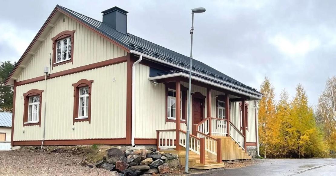 Vaalea kaksikerroksinen puutalo, jossa on viisi huonetta ja ruosteenväriset koristelaudat.