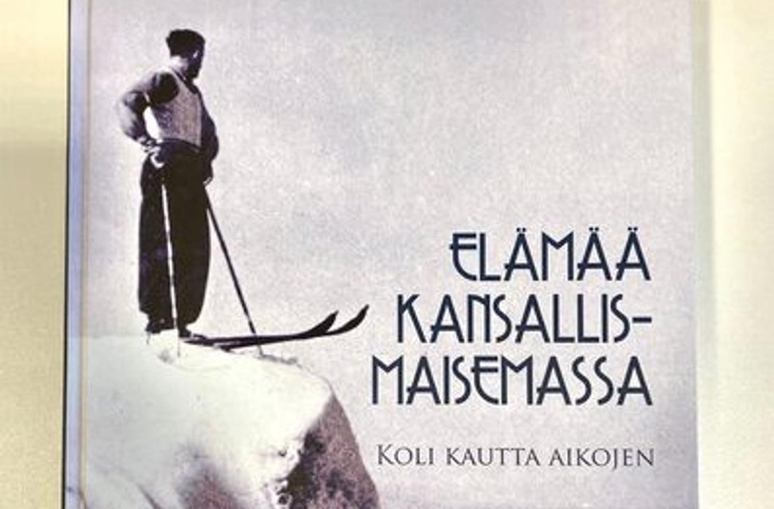 Koli kautta aikojen -kirjan kansi, jossa näkyy hiihtäjä Kolin kalliolla ja kirjan nimi.