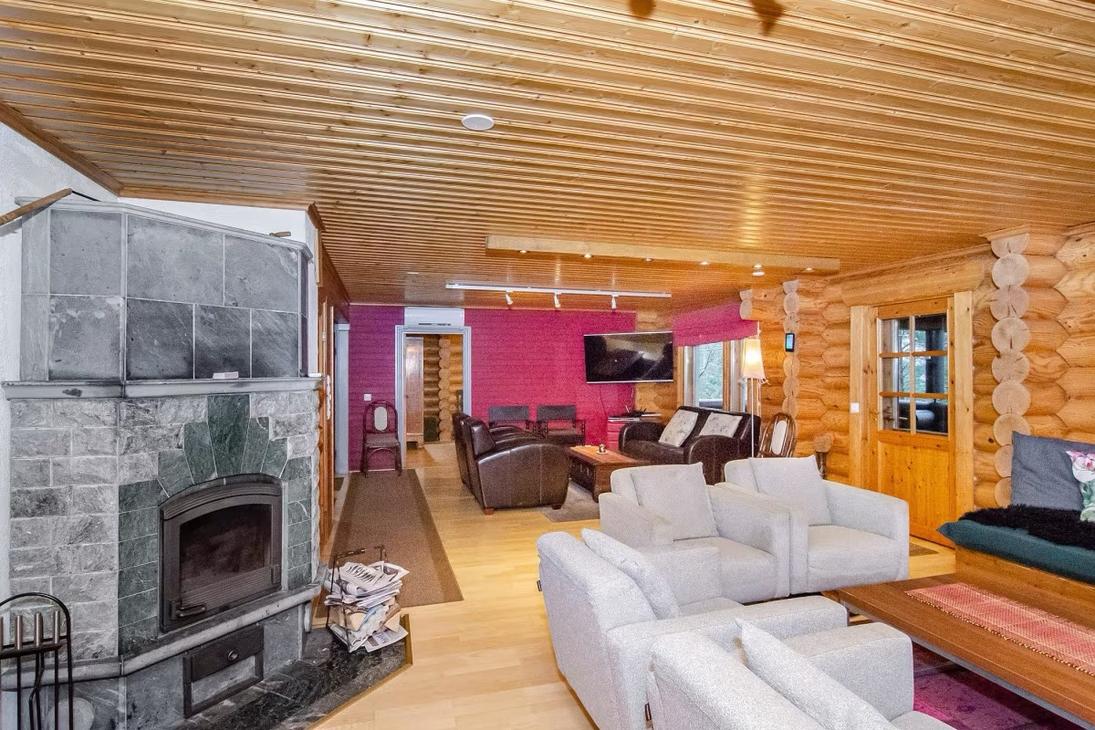 Tilava hirsiseinäinen olohuone ja takka, tumma ja vaalea sohvaryhmä