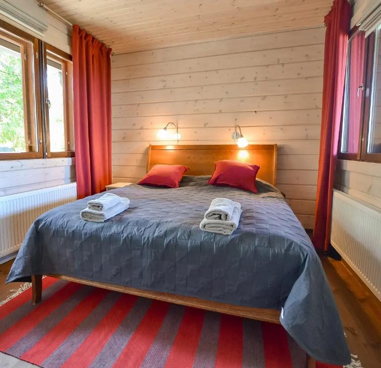 Makuuhuone parivuoteella, punainen tehosteväri verhoissa ja tyynyissä