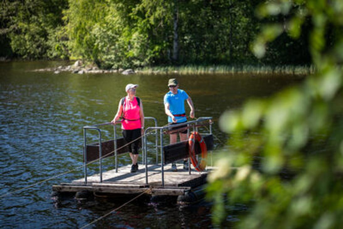 Kaksi retkeilijää vetolautalla ylittämässä vesistöä