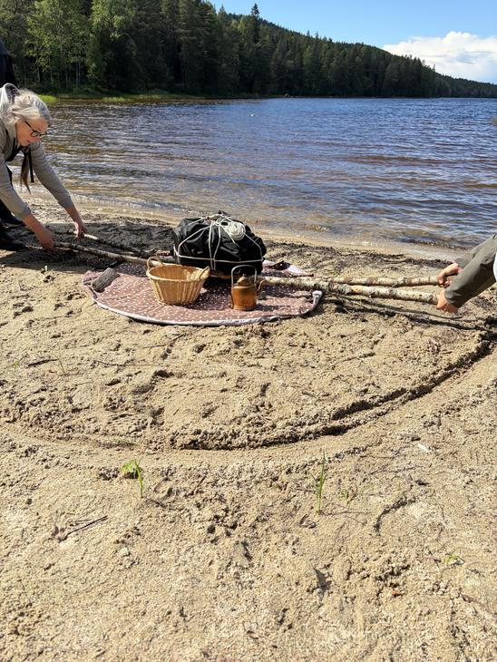 Hiekkarannalla nostetaan raskasta taakkaa keppien avulla