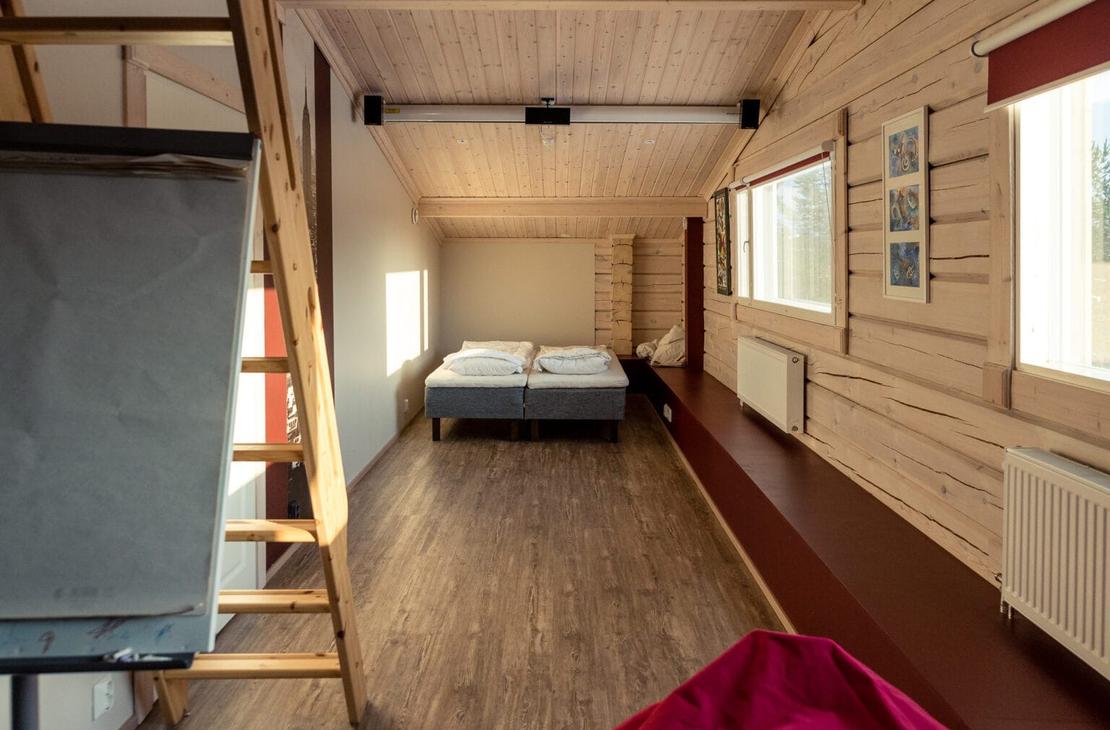 Pitkä elokuvahuone, jossa valkokangas ja kaksi sänkyä